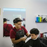 A man cutting another man's hair in a barber shop